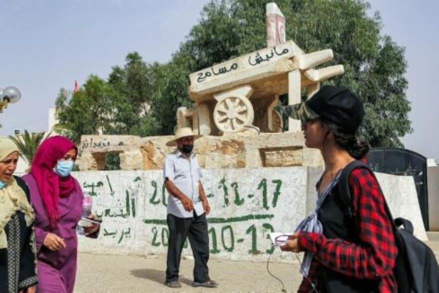 مواطنين يمرون اما تمثال لعربة محمد بوعزيزي