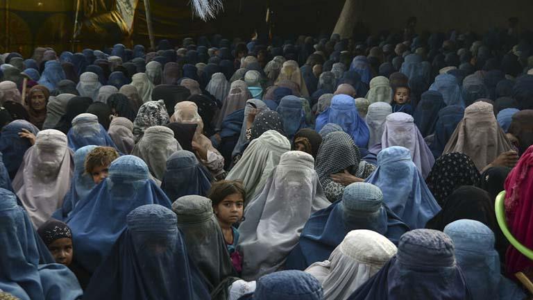 نساء وأطفالهن ينتظرن تلقي مساعدات غذائية في قندهار