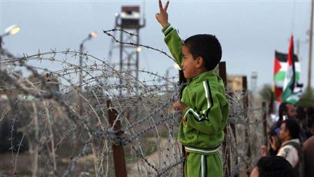 طفل فلسطيني يقف امام السياج الفاصل