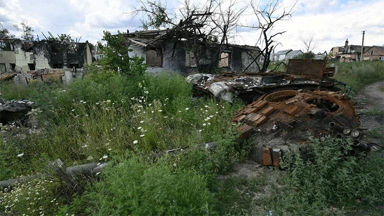 هيكل دبابة روسية مدمرة قرب منزل مهدوم في قرية مالا