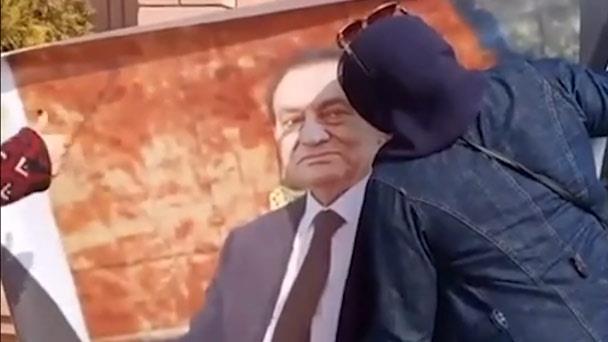 سيدة تُقبل صورة مبارك أمام قبره