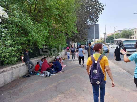 زوار حديقة الحيوان يفترشون الرصيف بجوار أسوارها في