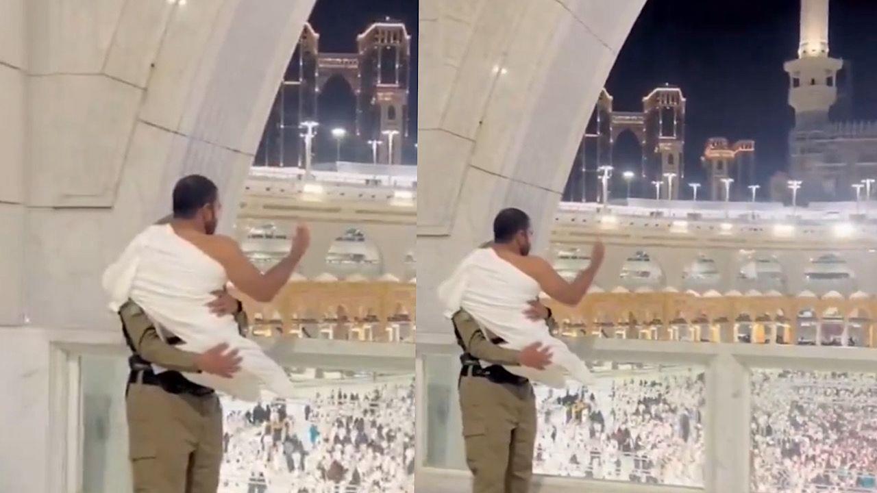 رجل أمن سعودي يحمل معتمرًا ليشاهد الكعبة