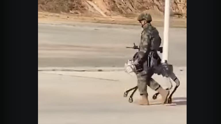 جندي صيني يتجول مع آلي مزود بسلاح