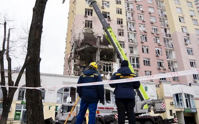 يقف رجال الإنقاذ الأوكرانيون أمام مبنى سكني متضرر في أعقاب هجوم روسي بطائرة مسيرة وصاروخ في كييف،_10