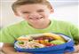 Young boy holding packed lunch in living room smiling