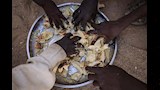 أطفال لاجئون سودانيون من الفاشر نزحوا بسبب الصراع الدائر في السودان يتناولون وجبة مجانية من العصيدة والخبز من طبق واحد في مخيم الطينة في شرق تشا