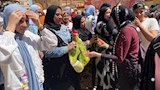إحدى السيدات توزع الشيكولاتة على الطالبات فرحة بانتهاء الامتحانات