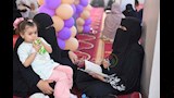 الطالبة تسرد القرآن وطفلتها على قدميها