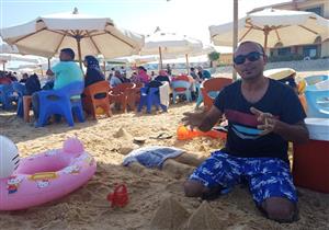 درس على رمال "السخنة".. أب يُعلم أطفاله بالرسم (صور)