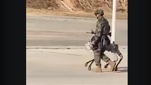 أسلحة المستقبل.. جندي صيني يتجول مع كلب آلي مزود بسلاح ناري (فيديو)