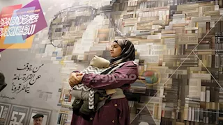 صورة اليوم بمعرض الكتاب.. مترجمة لغة الإشارة تحمل رضيعها أثناء عملها 