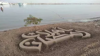 فنان سيناوي يودع شعبان بمجسم "أهلاً رمضان" على شاطئ البحر